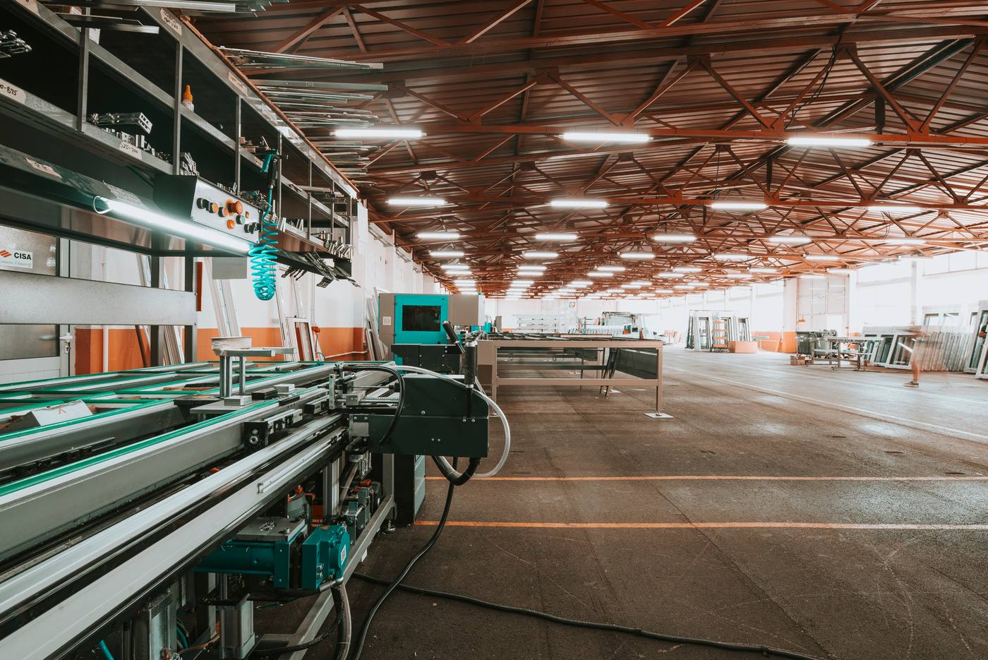 A large modern factory production hall with an open floor, painted lanes and a machine line running down one side.